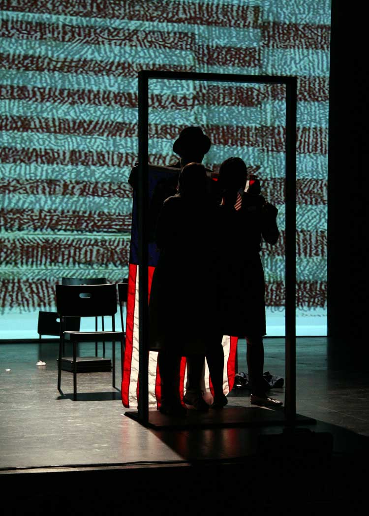 Three silhouetted figures wait at a door frame with an American flag hanging behind them.